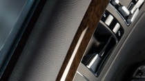 Close-up of a vehicle door panel with textured trim, wood-look accent, and window control switches.