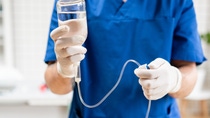 Doctor in blue uniform holding drip iv and infusion pump. Medical treatment emergency concept.. Intravenous fluid for seriously patient in the emergency room at hospital.
