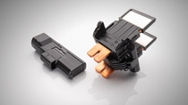 Two black electrical components on a reflective surface. The component on the right has orange coloured metal connectors. Two black electrical components on a reflective surface. The component on the right has orange coloured metal connectors.