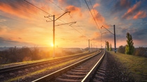 Railway station against beautiful sky at sunset. Industrial landscape with railroad, colorful blue sky with red clouds, sun, trees and green grass. Railway junction. Heavy industry. Evening in autumn Railway station against beautiful sky at sunset. Industrial landscape with railroad, colorful blue sky with red clouds, sun, trees and green grass. Railway junction. Heavy industry. Evening in autumn