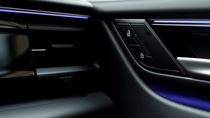 Vehicle interior door panel with lock controls and blue ambient lighting.
