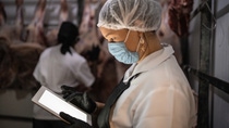 Female butcher using digital tablet with face mask at cold storage Female butcher using digital tablet with face mask at cold storage