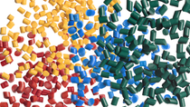 Red, yellow, blue, and green plastic pellets clustered across a white background.