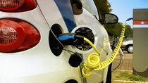 Electric vehicle charging cable connected to a car at a charging station.