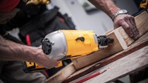 Woodwork Using Nail Gun. Caucasian Construction Worker Creating Wood Elements Using Powerful Nail Gun Tool. Woodwork Using Nail Gun. Caucasian Construction Worker Creating Wood Elements Using Powerful Nail Gun Tool.