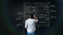 Thoughtful teacher staring at a blackboard while holding a chalk in his hand Thoughtful teacher staring at a blackboard while holding a chalk in his hand