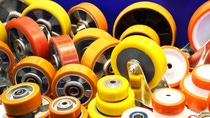 Assorted polyurethane wheels and rollers in yellow and orange with bearings for industrial handling equipment. Assorted polyurethane wheels and rollers in yellow and orange with bearings for industrial handling equipment.