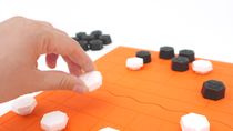 A player moves a Xiangqi piece on the orange game board, demonstrating the use of the custom game set made from BASF materials. A player moves a Xiangqi piece on the orange game board, demonstrating the use of the custom game set made from BASF materials.
