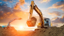 excavator in construction site on sunset sky background