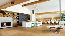 Modern open-plan living space with kitchen island, fireplace, dining area, and wooden interior details.