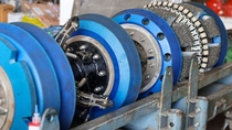 Industrial brush roller assembly with blue polyurethane wheels mounted on manufacturing equipment. Industrial brush roller assembly with blue polyurethane wheels mounted on manufacturing equipment.