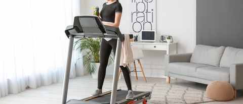 Sporty young woman training on treadmill at home