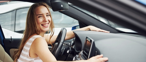Leans on the steering wheel and smiling. Female driver inside of modern automobile. Testing brand new car. Leans on the steering wheel and smiling. Female driver inside of modern automobile. Testing brand new car.