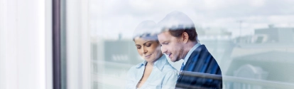 Business people standing behind glass wall using tablet computer