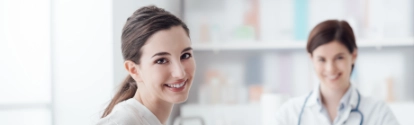 Smiling patient receiving a medical consultation and looking at camera, the female doctor is sitting at desk on the background