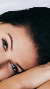 Young woman looking at camera and smiling while lying on the bed at home