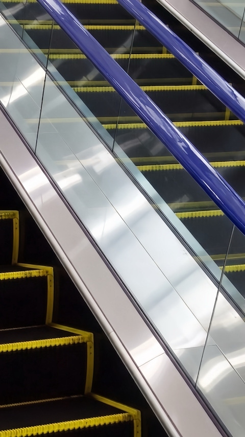 Escalator steps and handrails shown from above in a close-up view