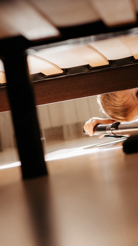 Little child using vacuum cleaner at home. Cute boy cleaning floor in bedroom