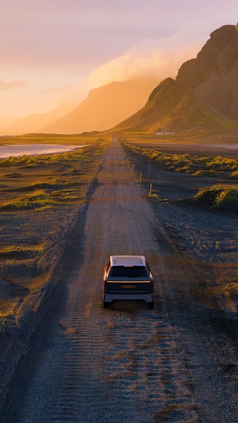 Gravel road at a golden Sunset with Vestrahorn mountain in the background and a car driving the road in Iceland Gravel road at a golden Sunset with Vestrahorn mountain in the background and a car driving the road in Iceland