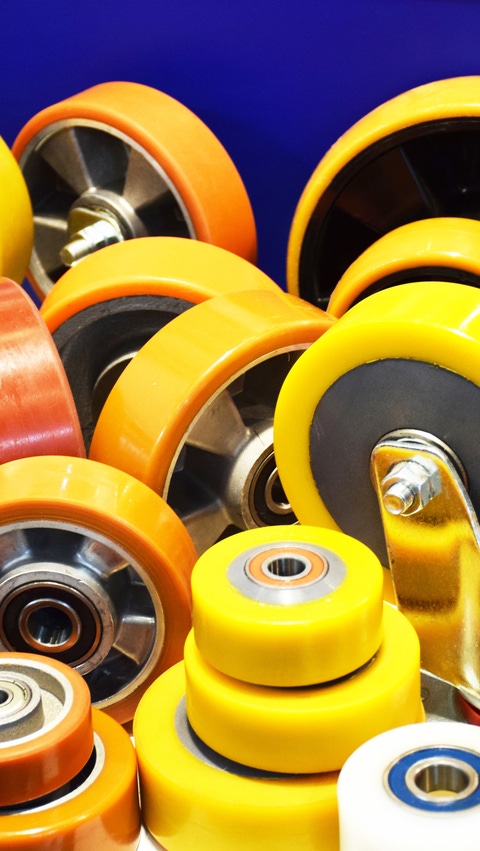 Assorted polyurethane wheels and rollers in yellow and orange with bearings for industrial handling equipment. Assorted polyurethane wheels and rollers in yellow and orange with bearings for industrial handling equipment.