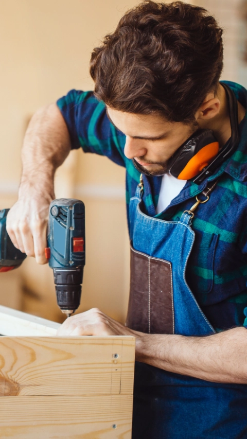 Carpenter drills a hole with an electrical drill