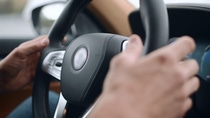 Driver holding a modern car steering wheel.