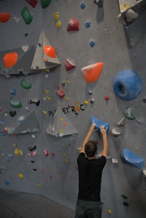 Close up of a man climbing a climbing wall in a gym