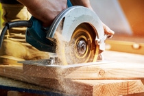 Building contractor worker using hand held worm drive circular saw to cut boards on a new home constructiion project Building contractor worker using hand held worm drive circular saw to cut boards on a new home constructiion project