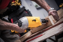 Woodwork Using Nail Gun. Caucasian Construction Worker Creating Wood Elements Using Powerful Nail Gun Tool. Woodwork Using Nail Gun. Caucasian Construction Worker Creating Wood Elements Using Powerful Nail Gun Tool.