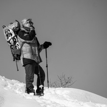 Image of Denis Bouvier in black and white where he is standing on a mountain in the snow on a sunny day Image of Denis Bouvier in black and white where he is standing on a mountain in the snow on a sunny day